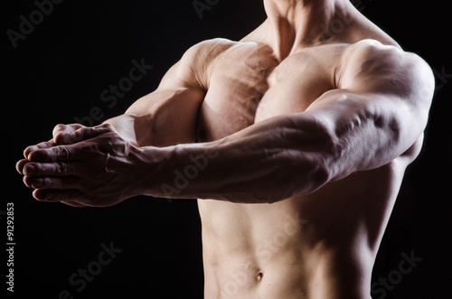 Muscular man posing in dark studio