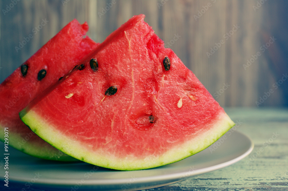 Fresh juicy slices of a watermelon on a plate on a wooden background. Fresh juicy slices of a watermelon on a plate on a wooden background.