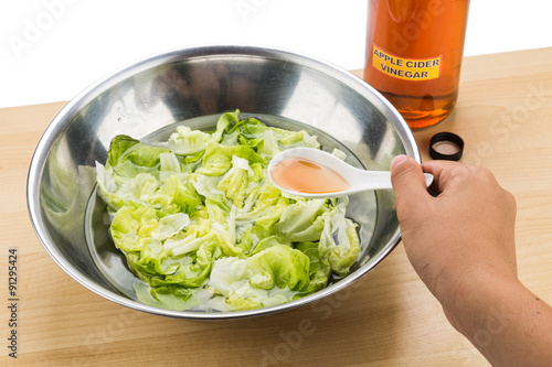 Fotografi Hand pouring spoonful of Apple Cider Vinegar to soak and remove pesticides resid