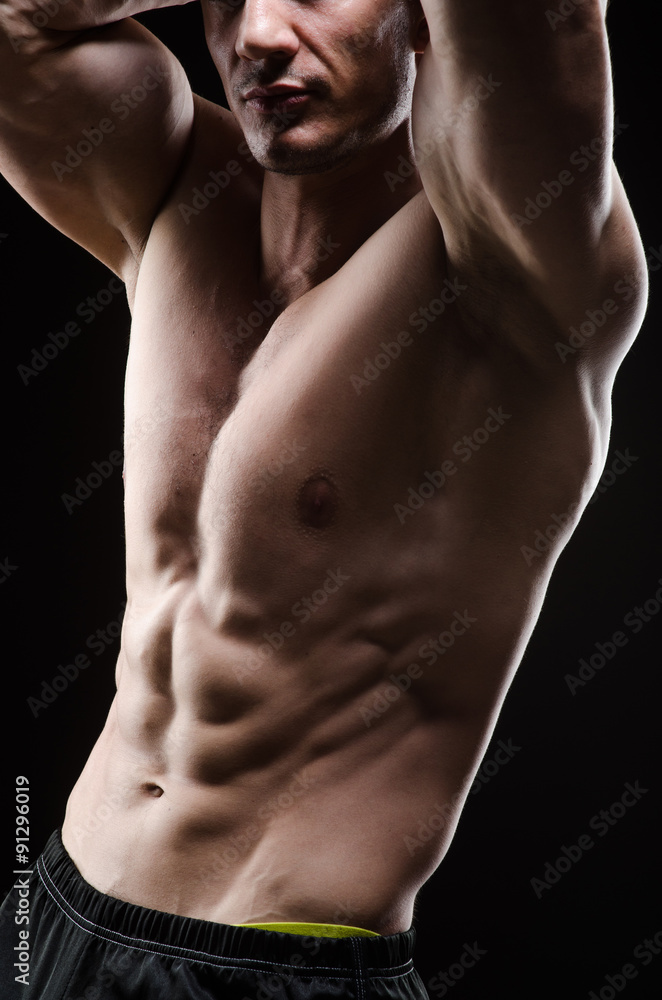 Muscular man posing in dark studio Muscular man posing in dark studio