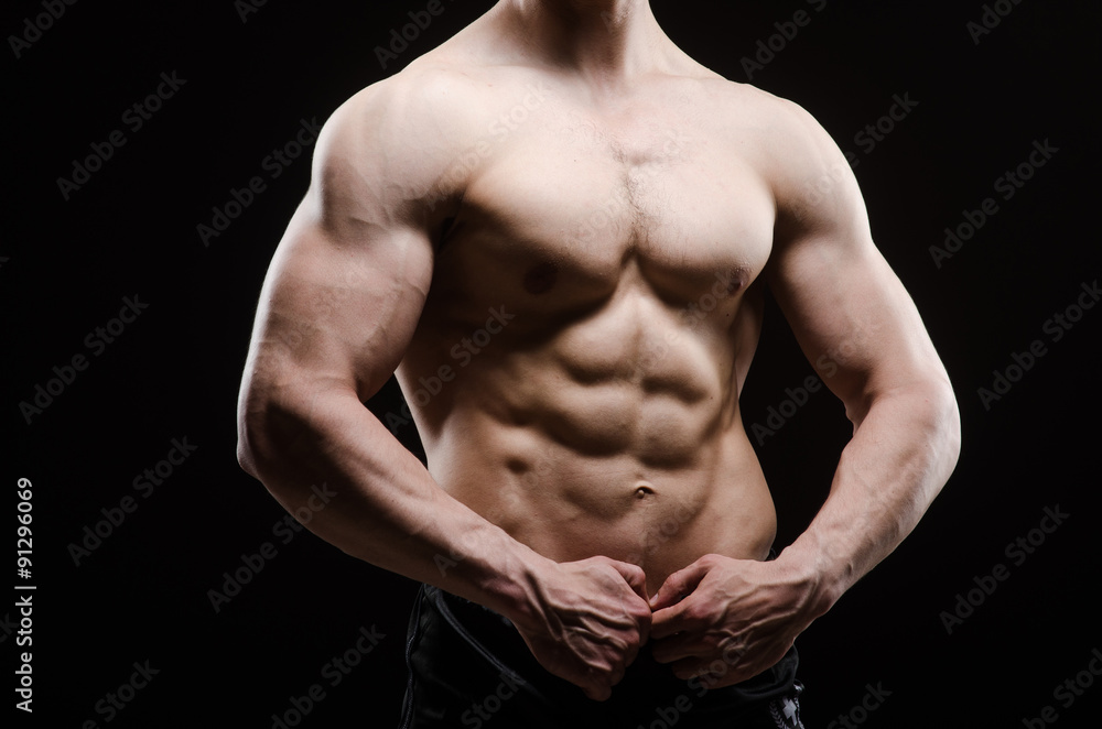 Muscular man posing in dark studio