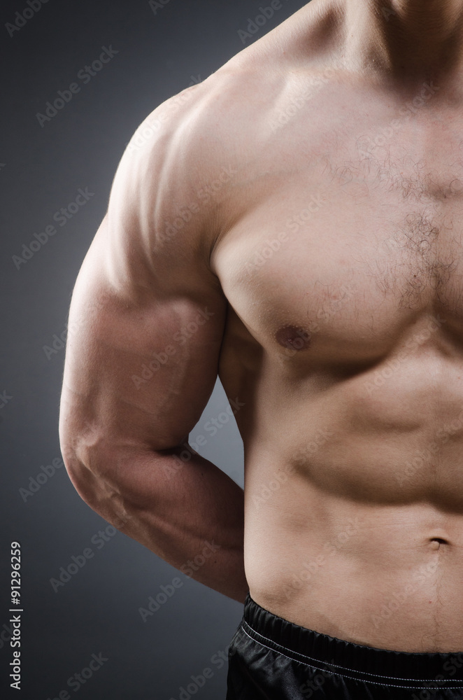 Muscular man posing in dark studio