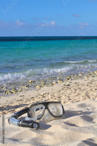 Snorkel and mask on the beach sand on the sea/sky background, sh