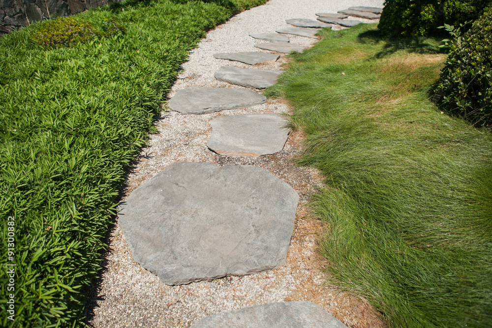 Stone walkway on a grass at the summer park