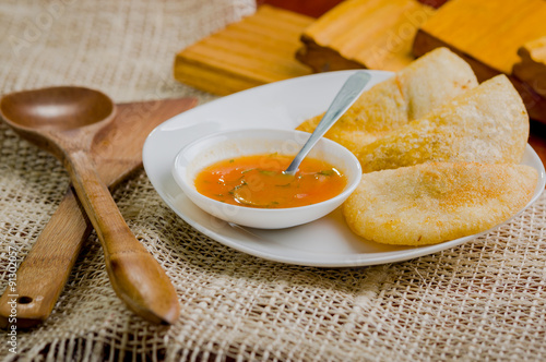 Three empanadas nicely arranged on white platter next to small photo