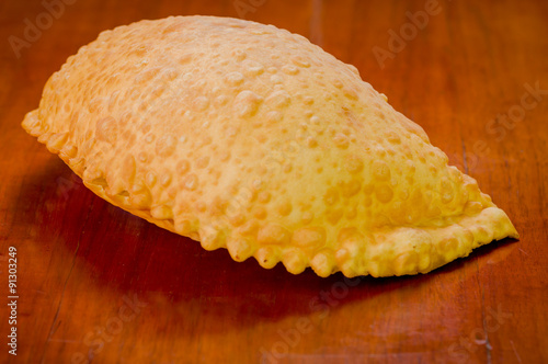 Large fluffy empanada beautiful color lying on wooden surface photo