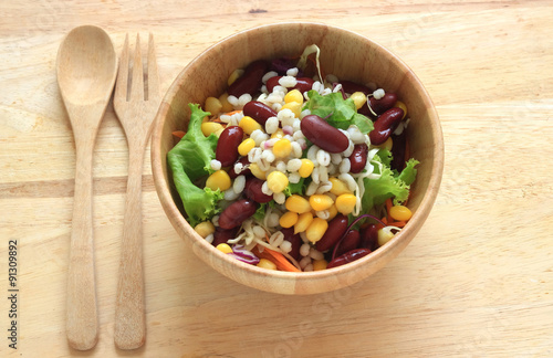 Healthy salad with fresh vegetables on wood background