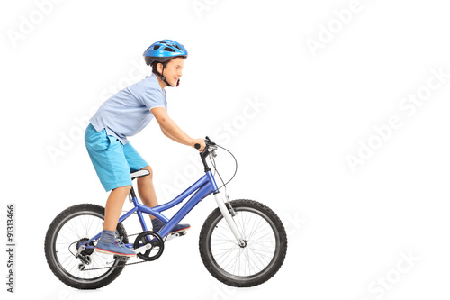 Llittle boy with blue helmet riding a small blue bike isolated o