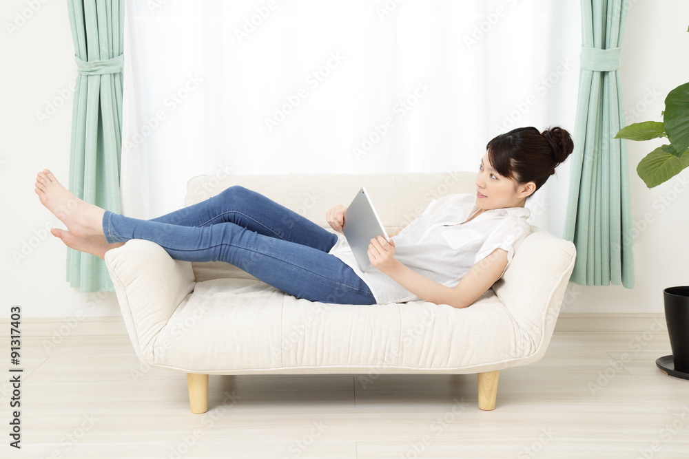 ソファーでタブレットを使っている女性 ソファーでタブレットを使っている女性