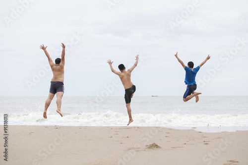 Three men jump on the beach