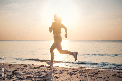 Running woman. Female runner jogging during the sunrise on beach.