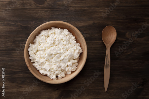 fresh tasty curd in pot on wooden background. Homemade, cottage cheese