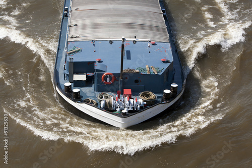 Fotografie Bow wave of a barge on the river