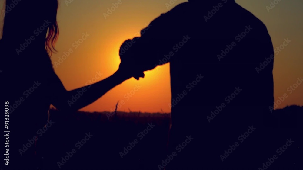 Silhouette of happy couple join hands runs across the field in Silhouette of happy couple join hands runs across the field in