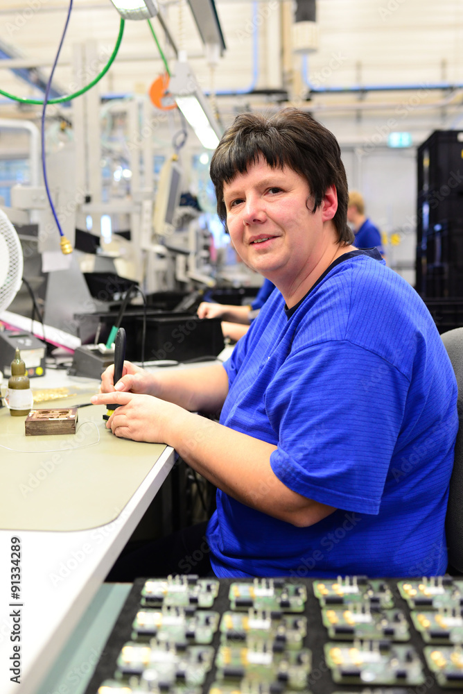 Worker in a factory mounted electronic components on the assembly line // Arbeiterin in einer