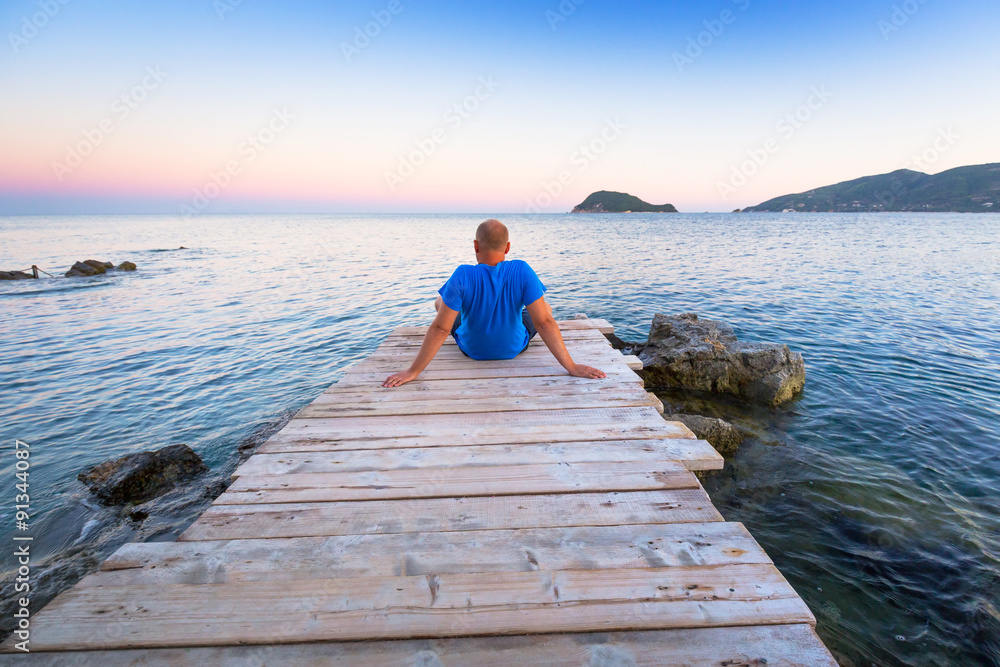 Man watching sunset over ionian sea in Greece Man watching sunset over ionian sea in Greece