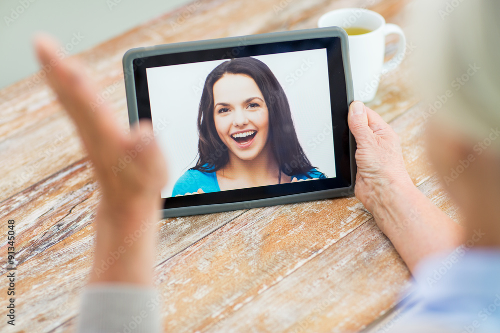 senior woman with photo on tablet pc at home