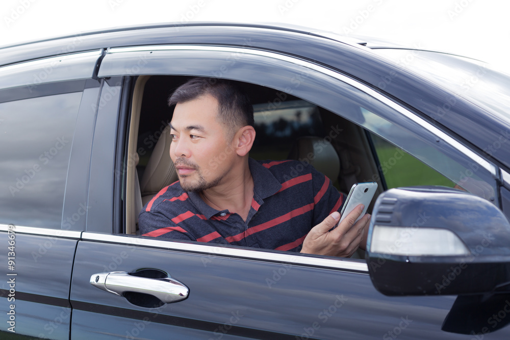 Asian man sitting in car and looking back