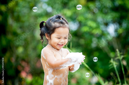 asian little girl having fun to play with water foam and bubble