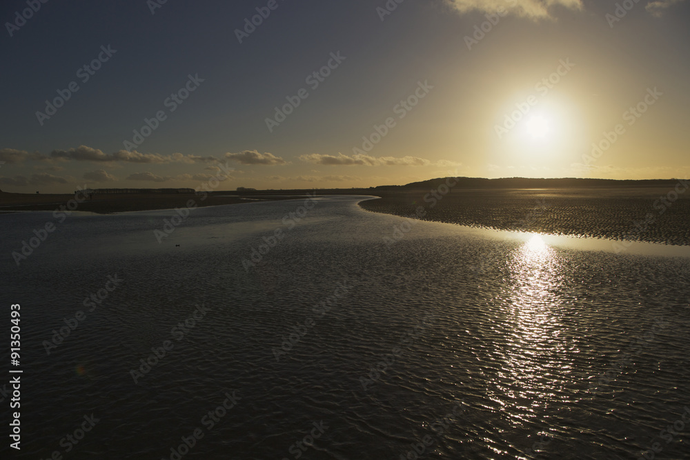 Sunset at Cadzand Belgium showing river flowing in north sea at sunset