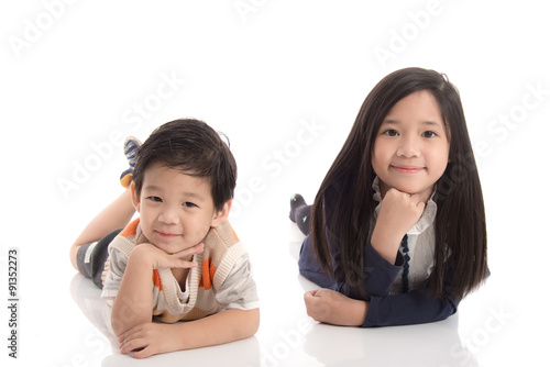 Two happy asian children lying and leaning on each other ,white background isolated © lalalululala