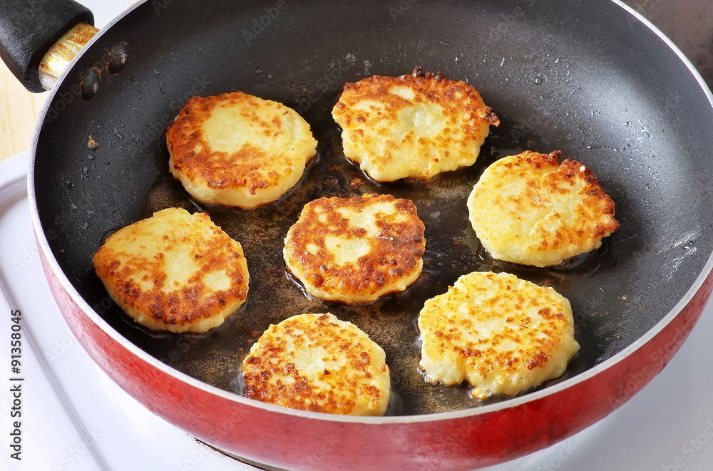 Beautiful golden cheese pancakes fried in a pan. Syrniki. 