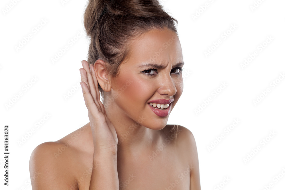 pretty young woman holding a hand behind the ear to better hear