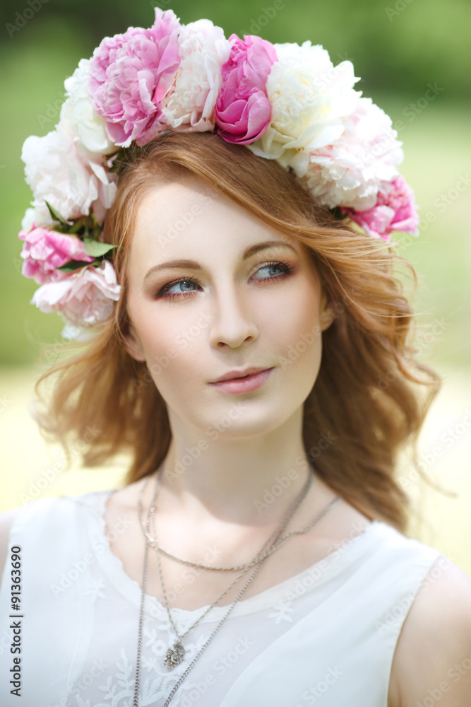 portrait of a beautiful girl in a wreath of peonies in nature