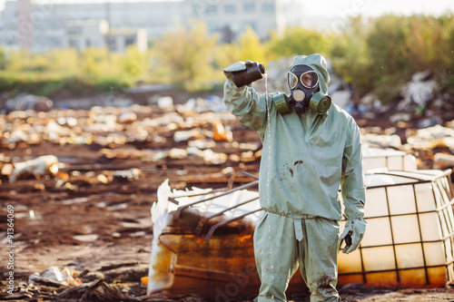 Man with gas mask and green military clothes explores barrels af