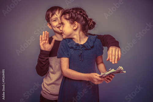 girl holding money bills in the hands of a boy trying to take aw photo