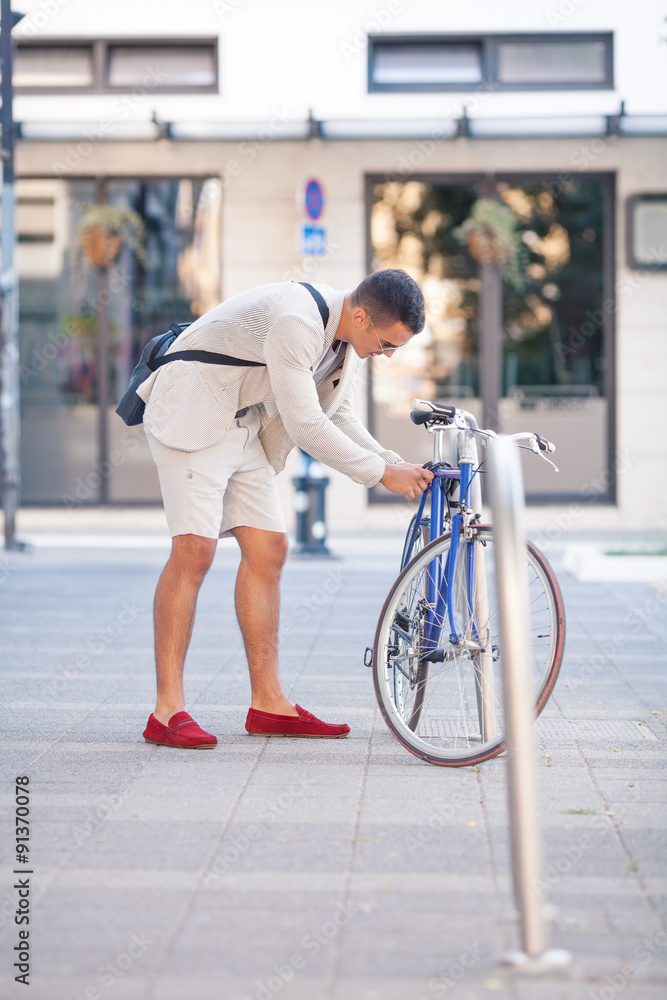 Young businessman locking his bicycle in front of the office building