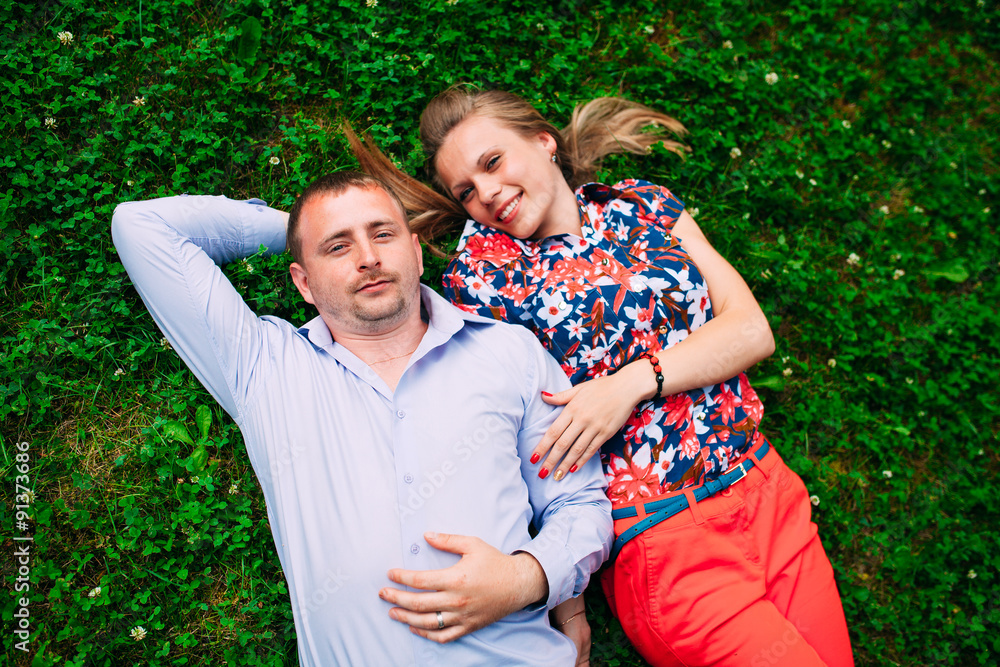 Young couple lying on the grass with a small dog Young couple lying on the grass with a small dog