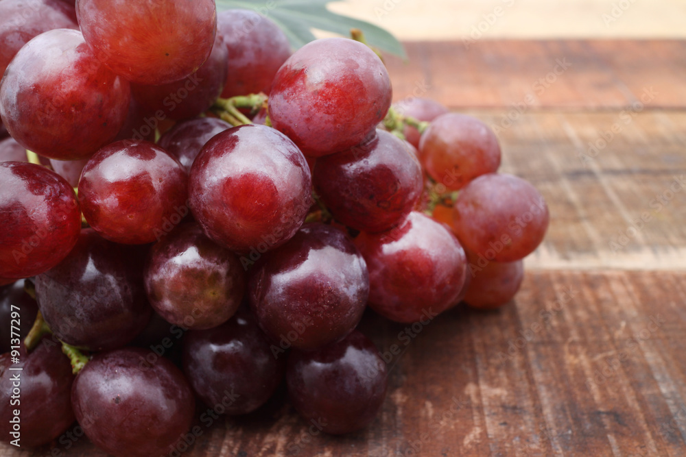 Bunch of red grapes on wooden table Bunch of red grapes on wooden table