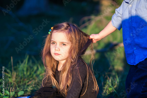 portrait of a beautiful little girl while her toddler brother is