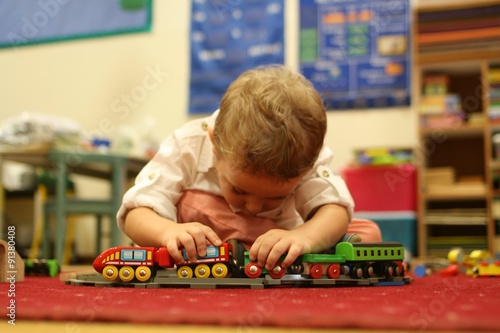 bambino molto concentrato gioca e si diverte a scuola con un trenino giocattolo photo