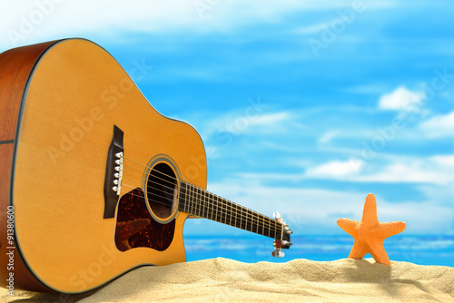 Fototapeta Naklejka Na Ścianę i Meble -  Acoustic guitar and starfish on the beach with blue sea and sky