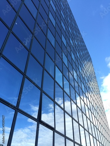 grattacielo di vetro che riflette cielo azzurro e nuvole
