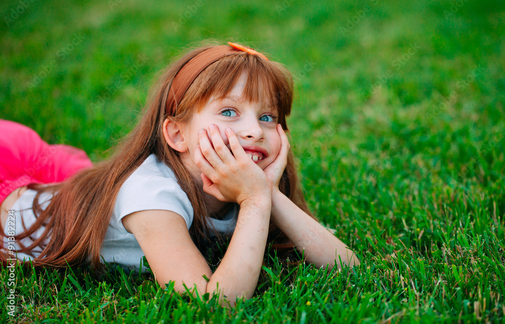 Fototapeta premium Little girl lying on the grass