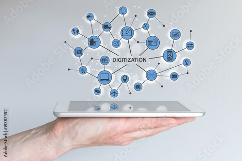 Digitization and digital disruption concept. Male hand holding modern tablet or smart phone with illustration of connected devices and information.