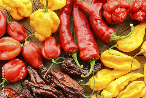 Various hot peppers viewed from the top on a wooden background.