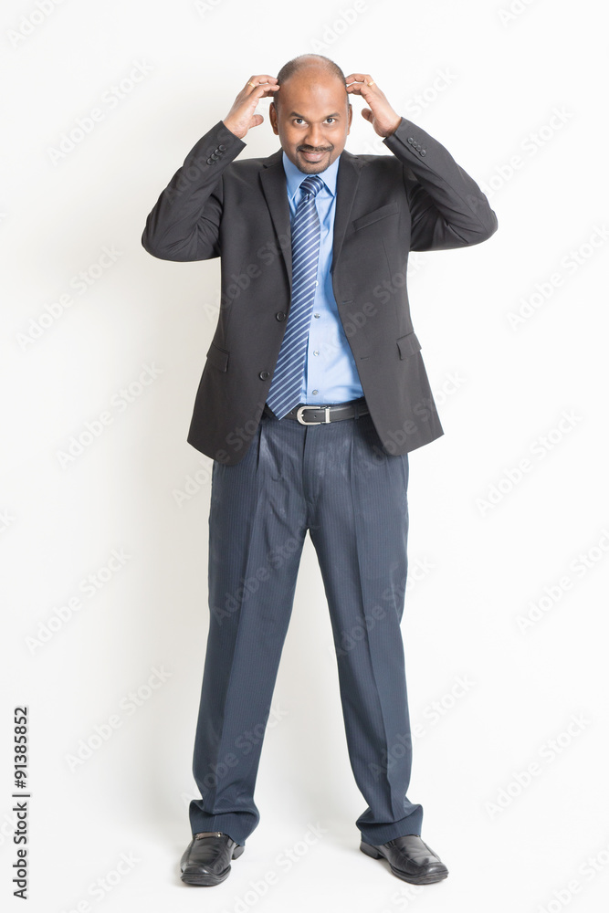 Full length mature Indian businessman scratching head Full length mature Indian businessman scratching head