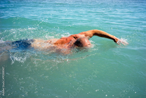 A man swims in the open sea © razoomanetu