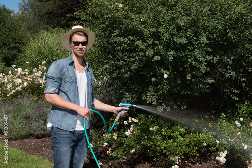 young handsome man is watering the plants