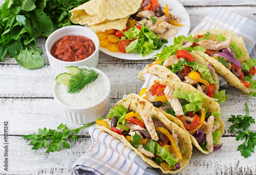 Mexican tacos with chicken, bell peppers, black beans and fresh vegetables.