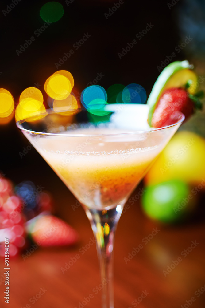 glass of bright tropical alcohol cocktail with passion fruit or lemonade with beautiful decoration on a table in a restaurant with backgrounds of bright colored lights. soft focus.