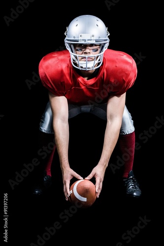 American football player bending while holding ball