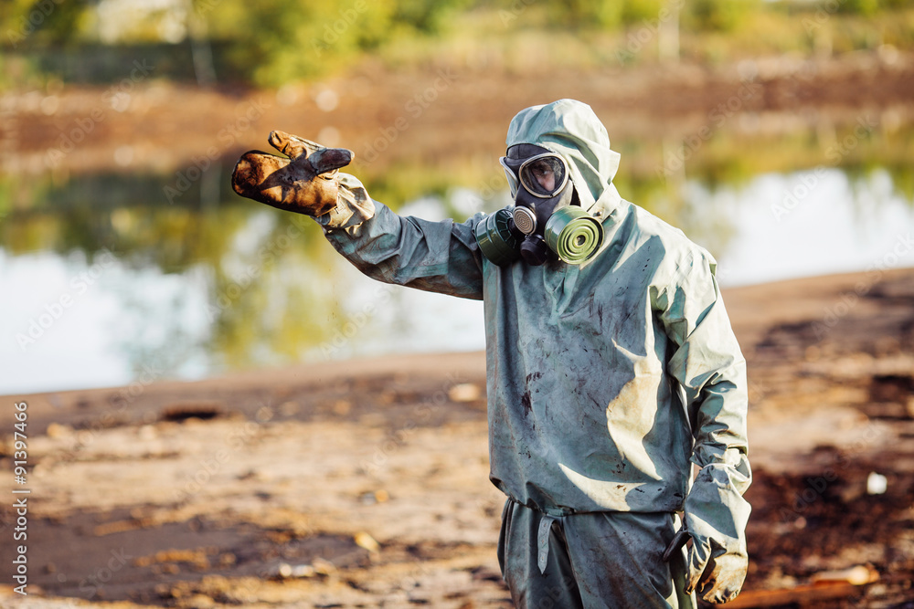 Man with gas mask and green military clothes explores barrels af