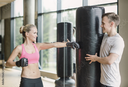 smiling woman with personal trainer boxing in gym © Syda Productions