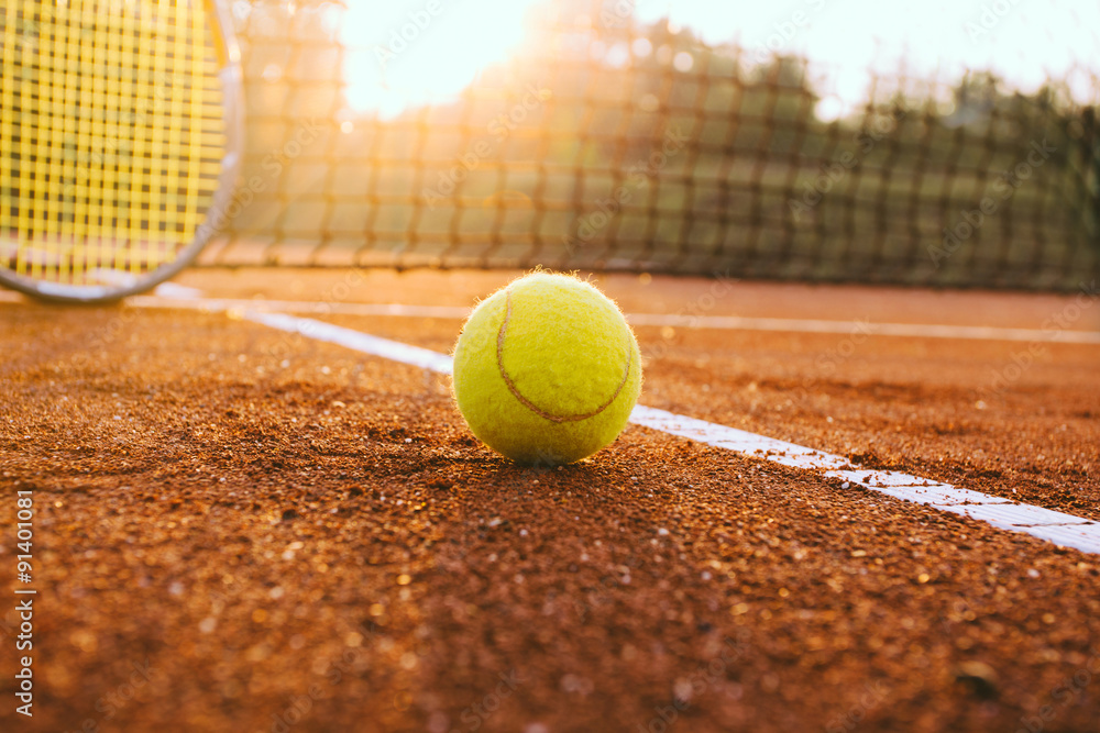 Tennis racket and ball on a clay court
