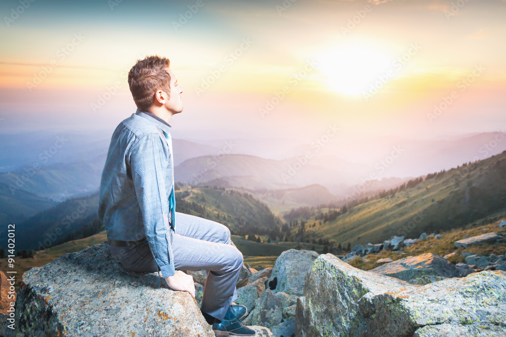 Naklejka premium businessman at the top of the mountain sitting and thinking